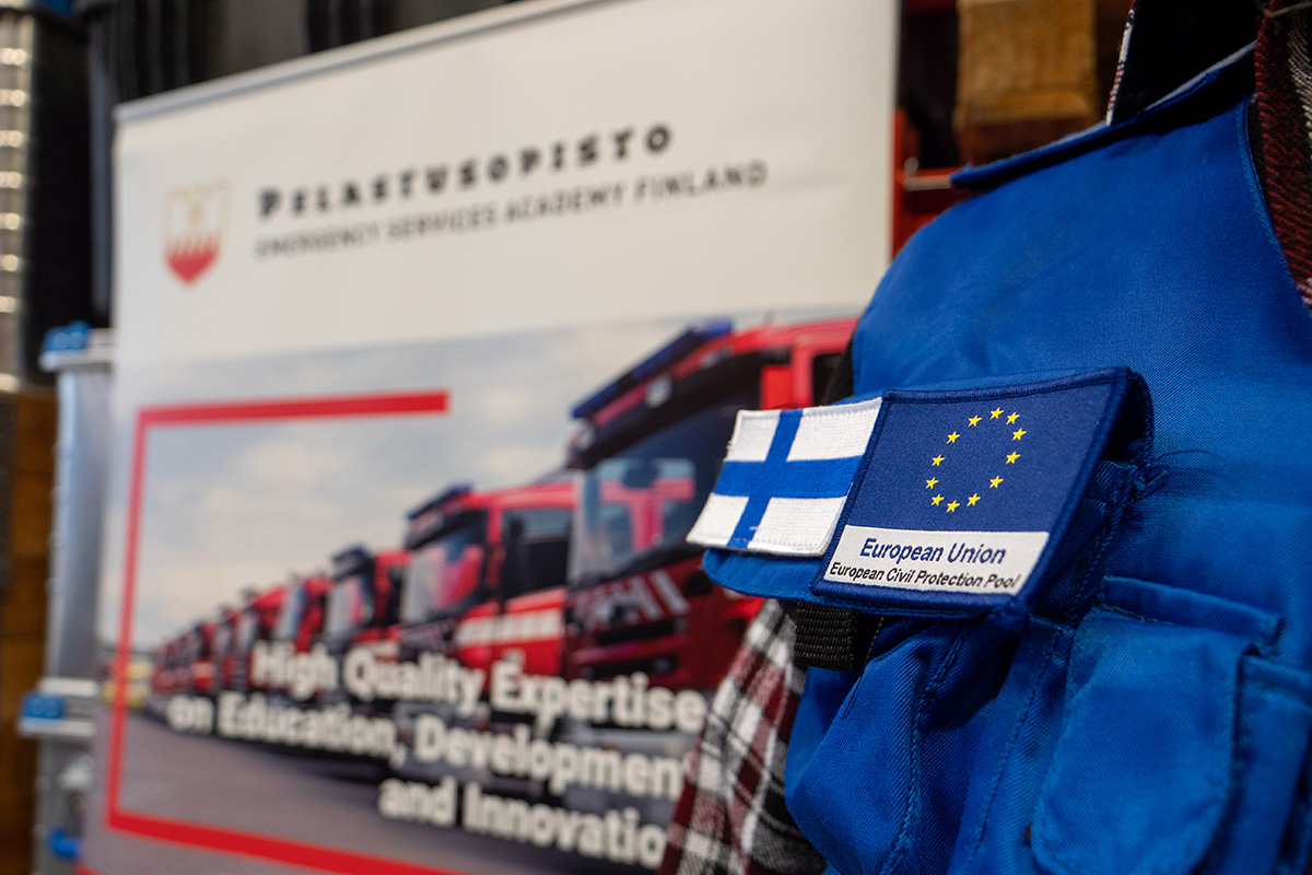 Lähikuva henkilön takista, jossa suomen lippu ja European Union - European Civil Protection Pool -lippu.