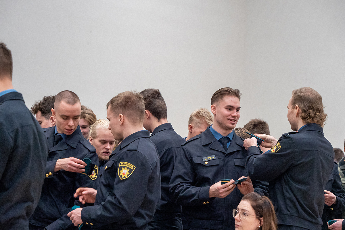 Pelastajaopiskelijat laittavat toisilleen olkatunnuksia.