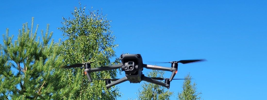 Drone lentää puiden latvuston tasalla.