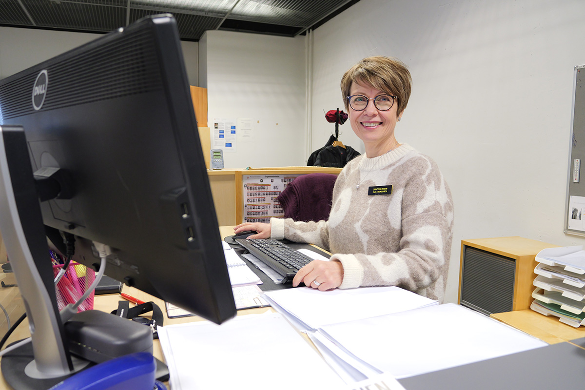 Opintosihteeri Eija Heikkinen hymyilee työpöytänsä ääressä.