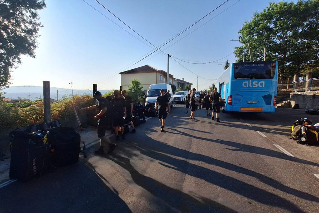 Henkilöstöä matkatavaroineen maantien sivustalla, teiden reunoilla myös linja-auto ja muita ajoneuvoja.