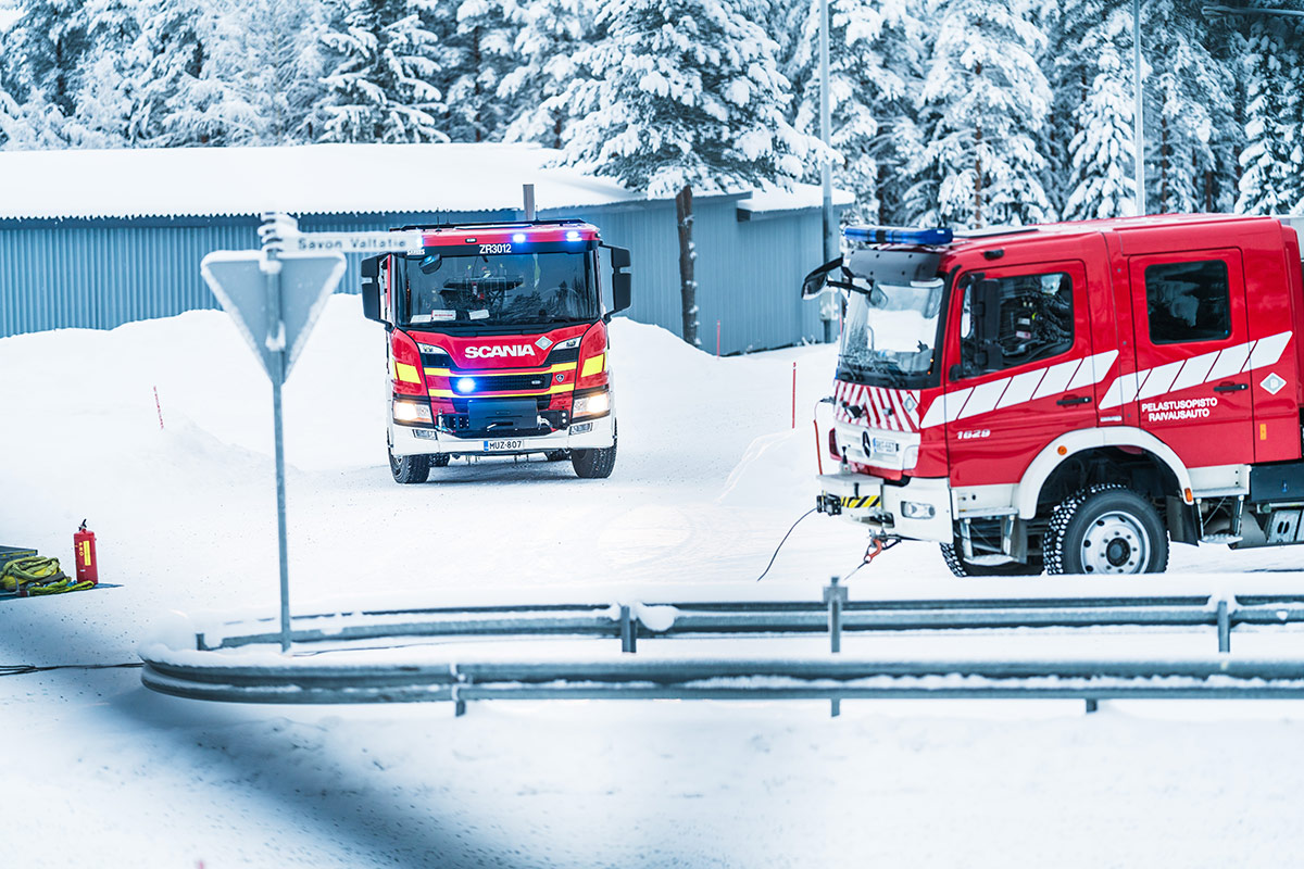 Talvinen maisema Pelastusopiston harjoitusalueella. Kaksi sammutusautoa tienristeyksessä.