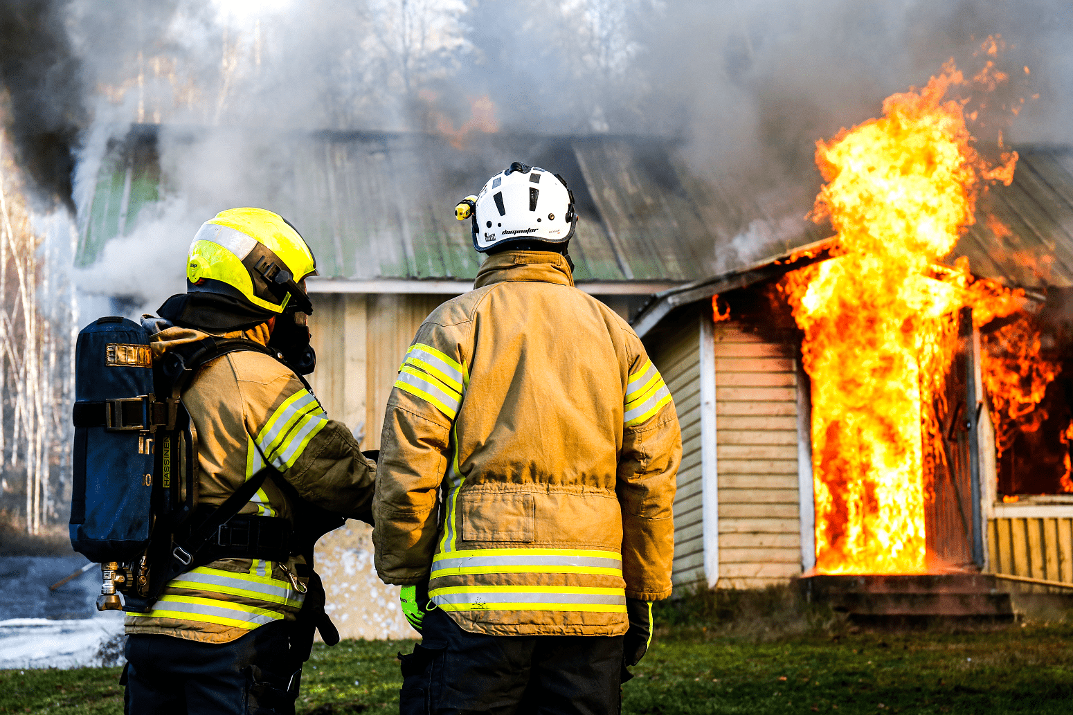 Kaksi pelastusalan ammattilaista palavan talon edessä.