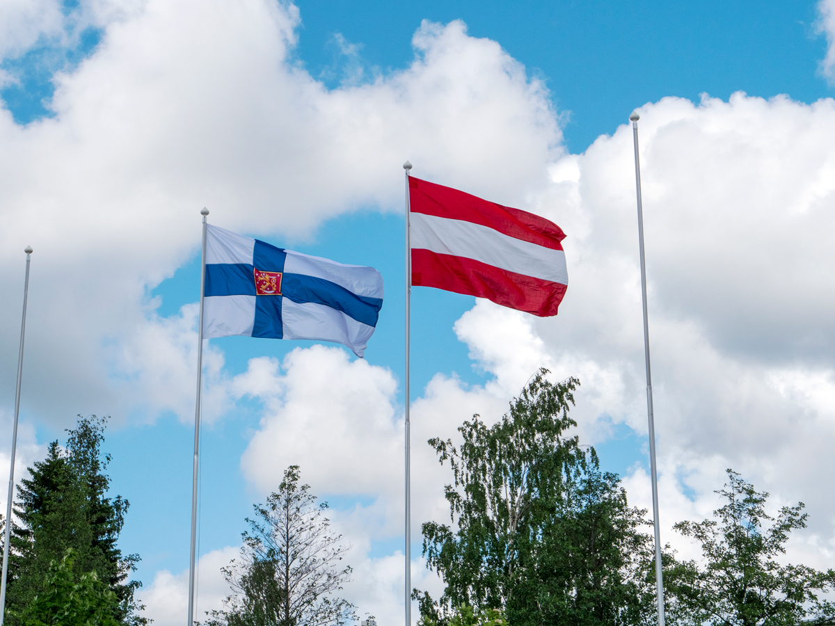 Suomen ja Itävallan liput liehuvat tangoissa.
