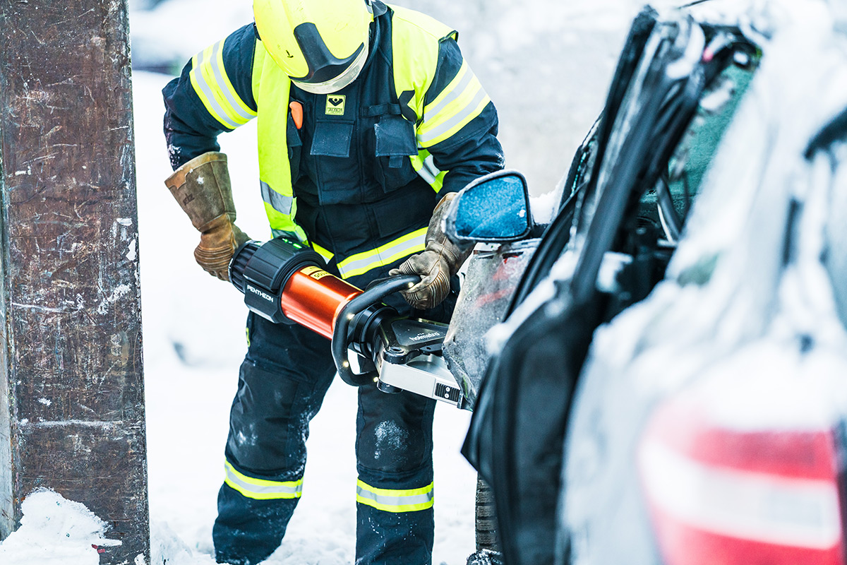 Pelastaja leikkaa kolariin joutunutta autoa auki leikkurilla.