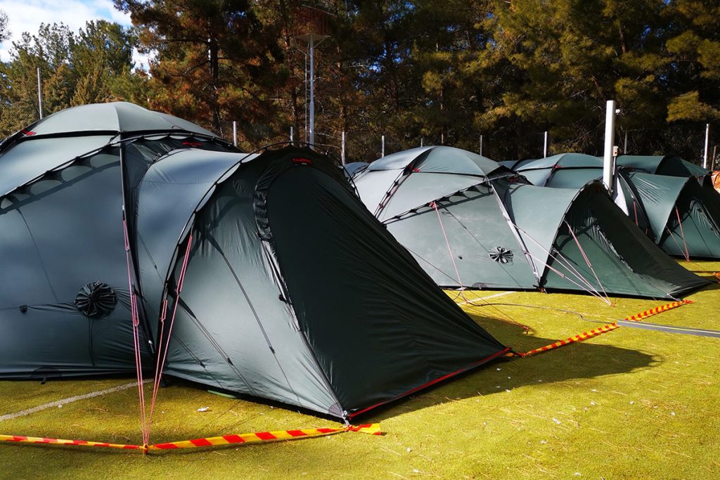 Vihreitä telttoja kasattuna vierekkäin metsän laitaan.