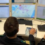 Pelastustoimen henkilöitä tietokonepöydän ääressä, edessä useita näyttöjä.