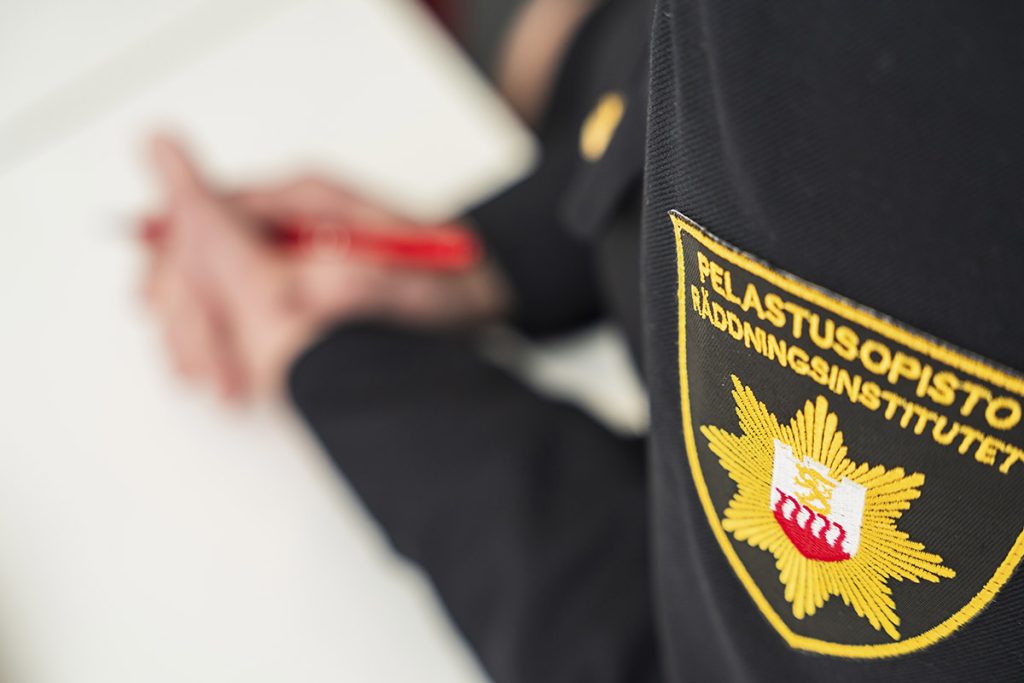 Virkapuvussa olevan henkilön kädet, hihan ja hihamerkki.