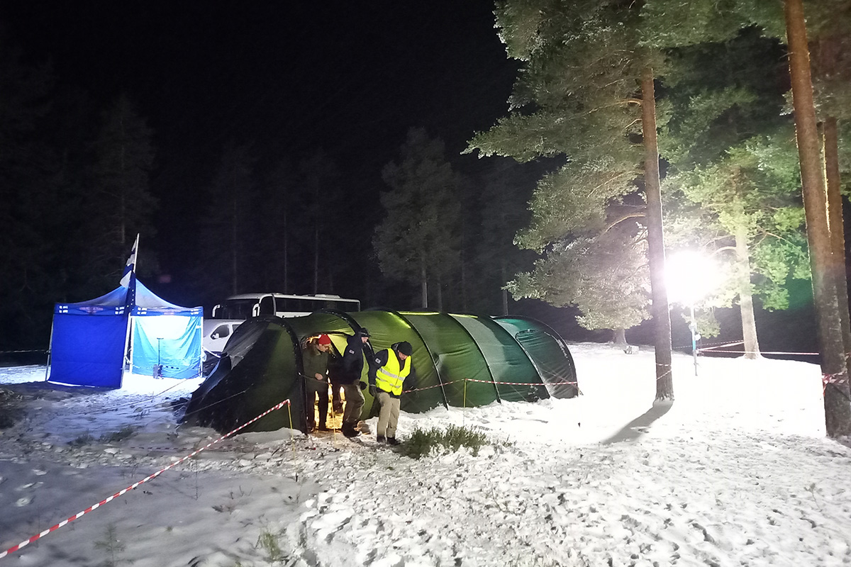 Kolme henkilöä astumassa teltasta ulos.