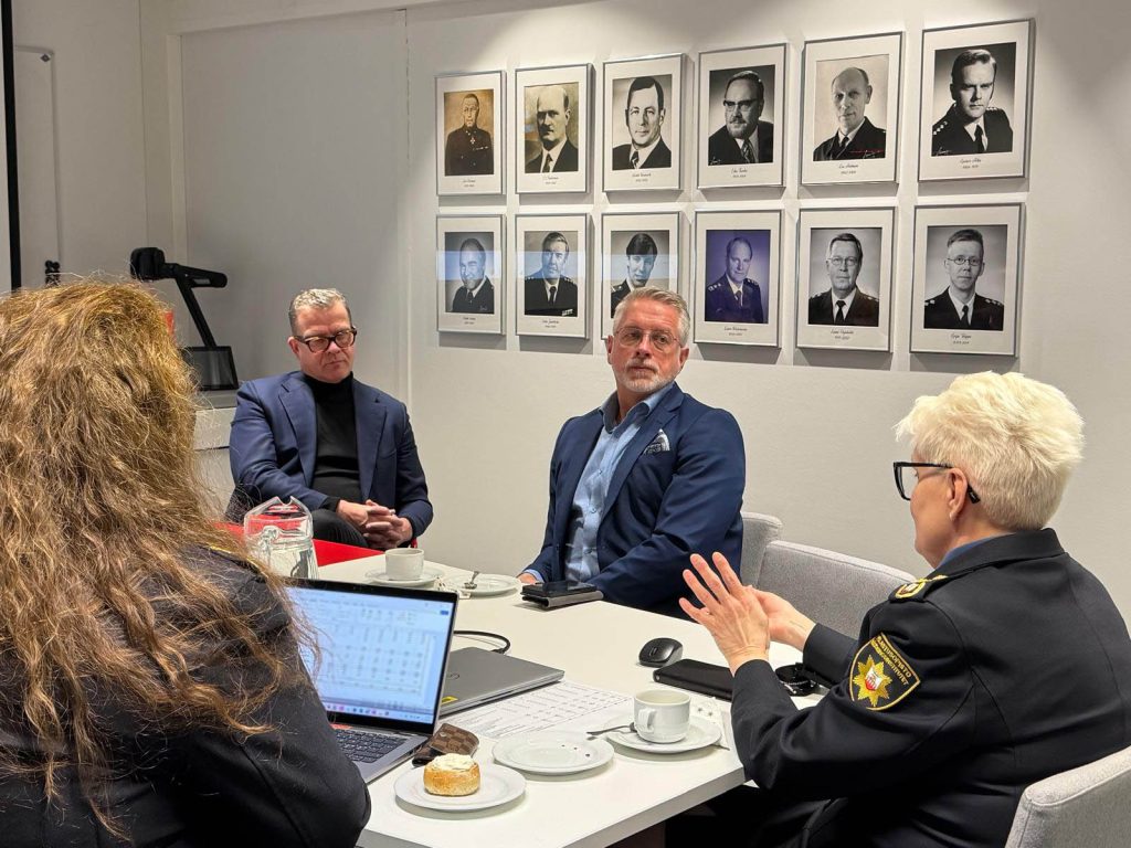 Pääministeri Petteri Orpo seurueineen ja Pelastusopiston edustajat keskustelevat neuvotteluhuoneessa.