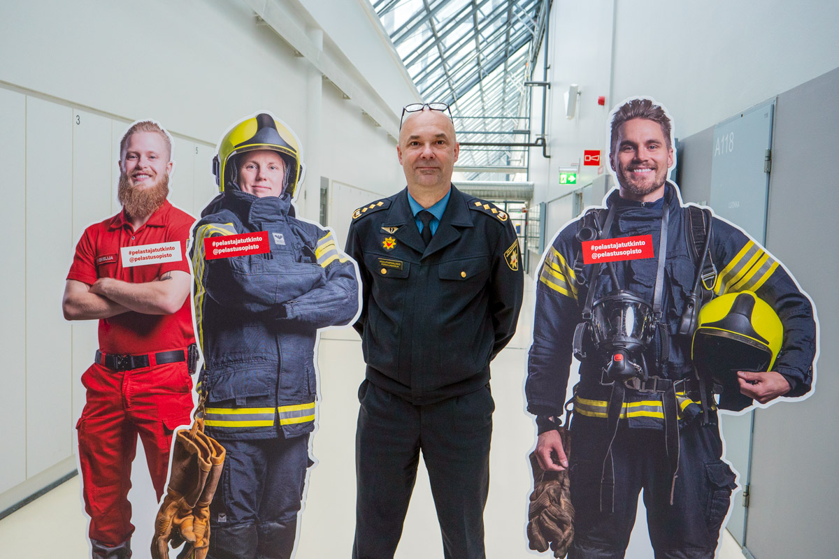 Pekka Lindholm seisoo kolmen pelastajaopiskelijaa kuvaavan pahvihahmon keskellä.