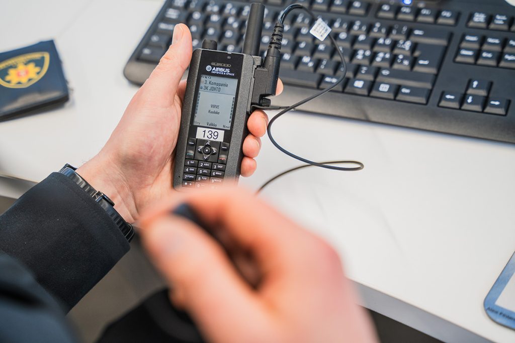 Lähikuva Virve-puhelinta pitelevästä kädestä.