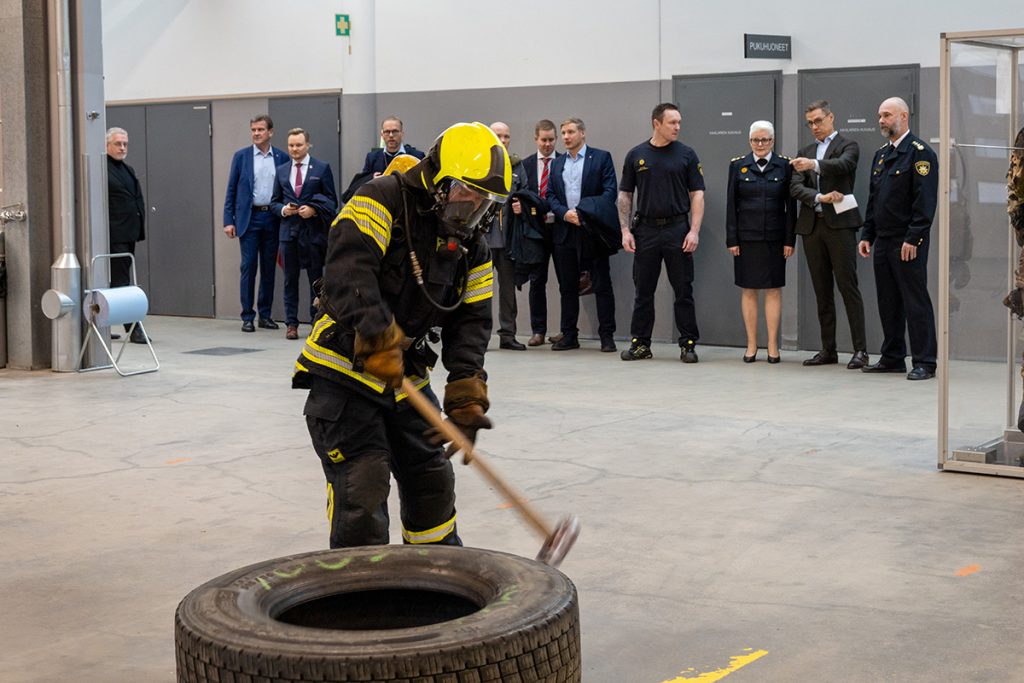 Vierailijat seuraavat pelastajaopiskelijan testisuoritusta, jossa rengasta siirretään lyöden lekalla.