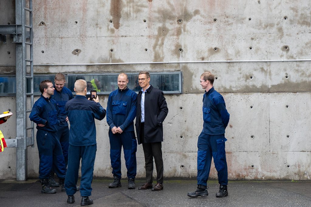 Pelastajaopiskelijat ottavat yhteiskuvia tasavallan presidentin kanssa kalustopihalla.