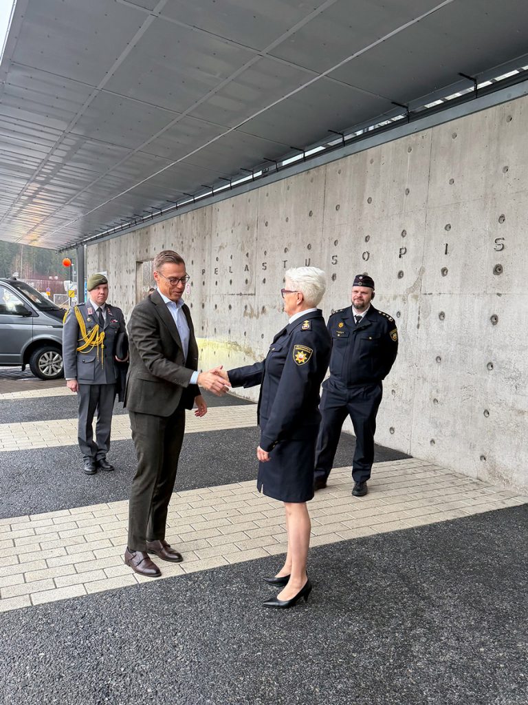 Tasavallan presidentti ja Pelastusopiston rehtori kättelevät pääoven edustalla.