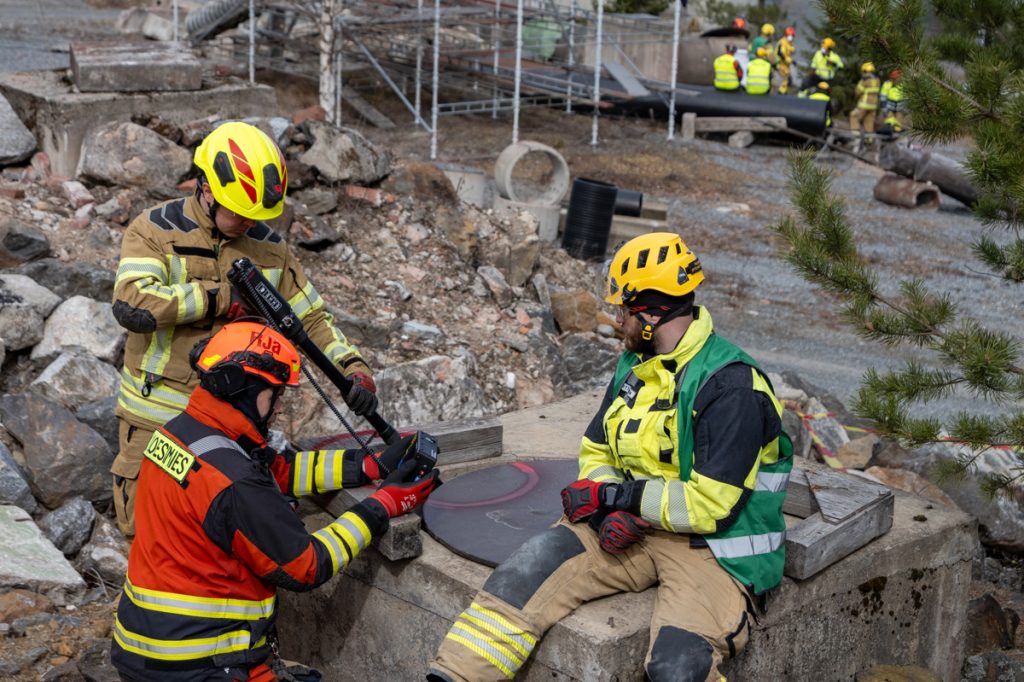 Kolme pelastustoimen henkilöä kaivon äärellä.