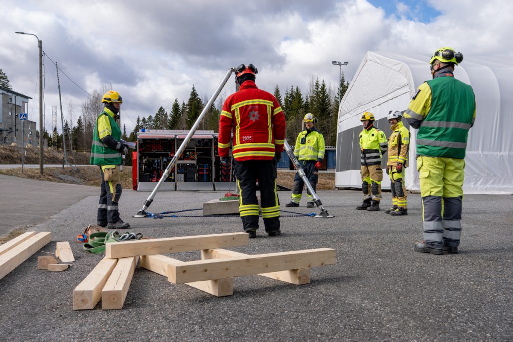 Pelastustoimen henkilöitä kokoontuneena asfaltoidulle aukealle.