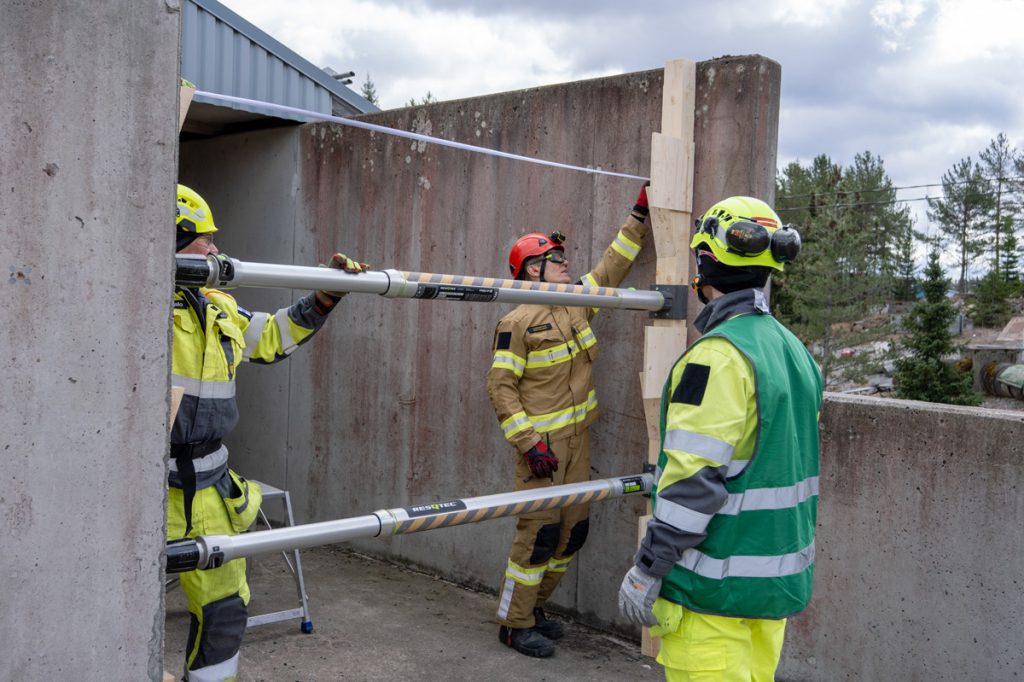 Kolme pelastustoimen henkilöä tarkastelemassa rakennuksen rakenteita.