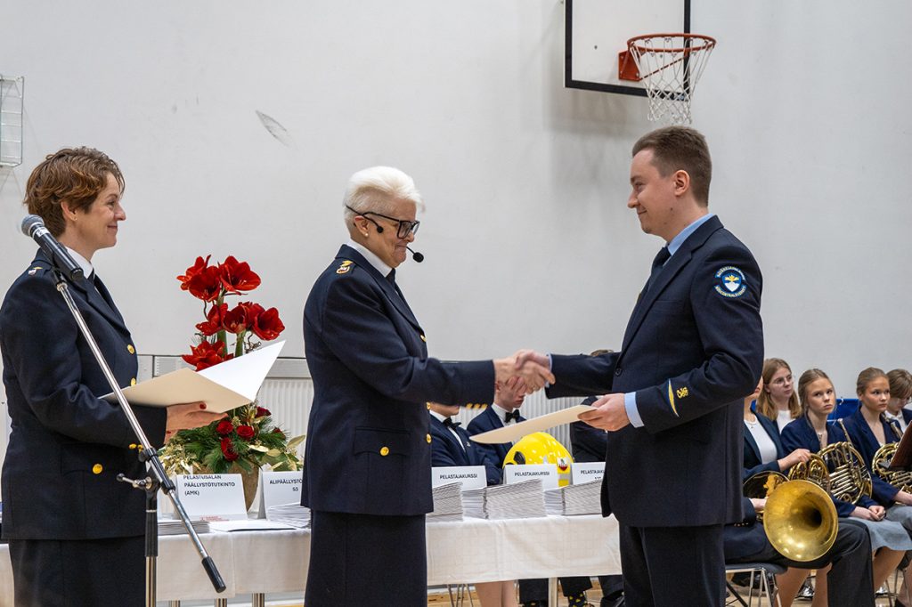 Rehtori kättelee valmistuvaa hätäkeskupäivystäjäopiskelijaa.