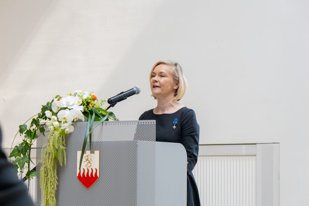 Henkilö pitää juhlapuhetta salin edessä.