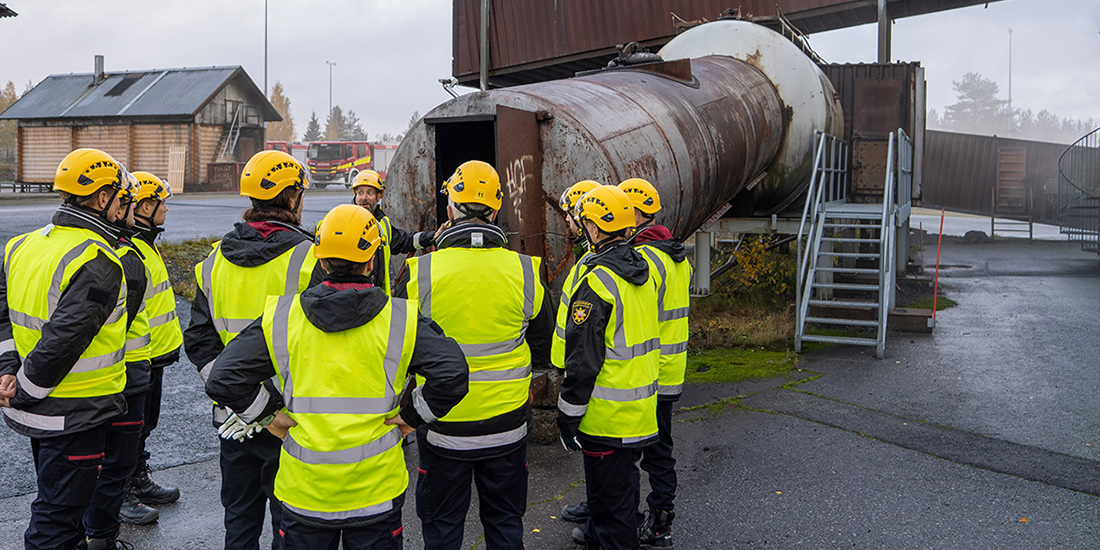 Ohjaaja esittelee Varsinais-Suomen hyvinvointialueen pelastuslaitoksen työntekijöille Pelastusopiston harjoitusalueen harjoituskohdetta.
